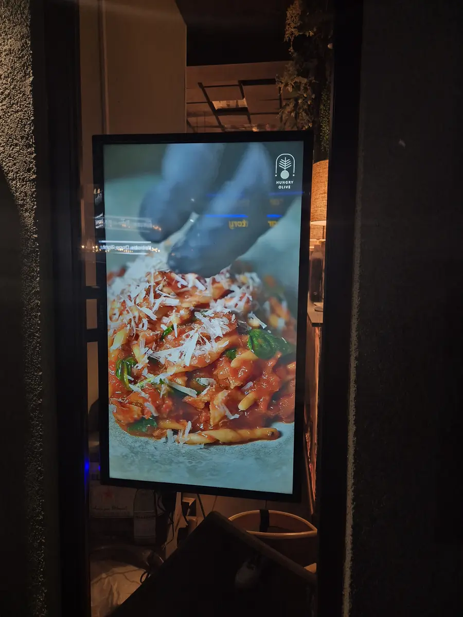 Wall-mounted digital signage in a café showing breakfast and coffee menu.